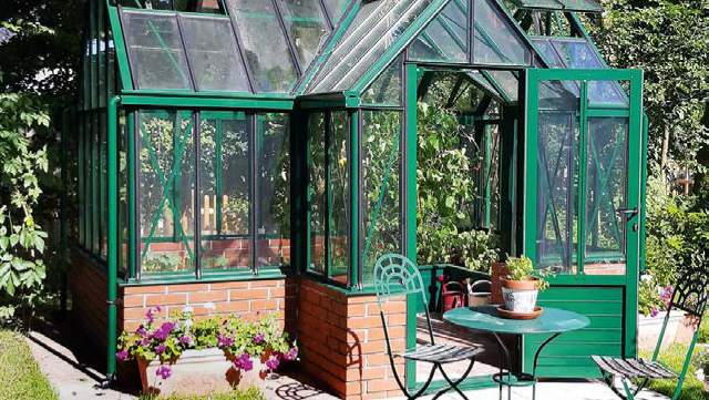 Glasgewächshaus mit grünen Pflanzen, Gartentisch und Stühlen auf sonniger Terrasse. HANSEL.kraus metalltechnik gmbh