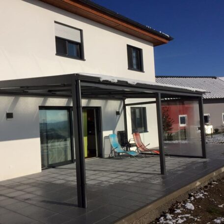 Modernes Einfamilienhaus mit überdachter Terrasse, großen Fenstern und Garten bei sonnigem Wetter. de HANSEL.kraus metalltechnik gmbh