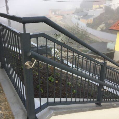 Treppengeländer mit Aussichtsplattform und Blick auf neblige Wohnhäuser in Hanglage. HANSEL.kraus metalltechnik gmbh