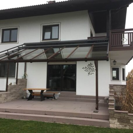 Modernes Einfamilienhaus mit Glasüberdachung, Terrasse und gepflegtem Garten, Tageslichtaufnahme. HANSEL.kraus metalltechnik gmbh