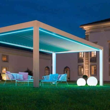 Moderne Terrassenüberdachung mit LED-Beleuchtung und Sitzmöbeln im Garten vor einem Gebäude bei Nacht. HANSEL.kraus metalltechnik gmbh