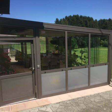Wintergarten mit Glasfront und Blick auf grünen Garten an sonnigem Tag. HANSEL.kraus metalltechnik gmbh