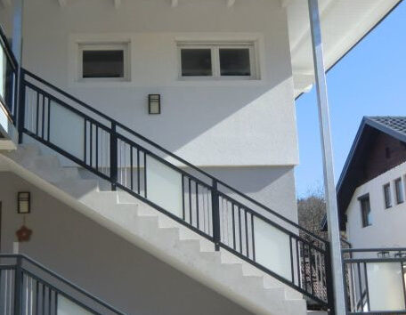 Treppe mit schwarzem Geländer führt an modernem, weißem Gebäude entlang nach oben. HANSEL.kraus metalltechnik gmbh