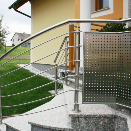 Edelstahlgeländer an moderner Hauseingangstreppe mit Sichtschutz, Vorgarten im Hintergrund. de HANSEL.kraus metalltechnik gmbh