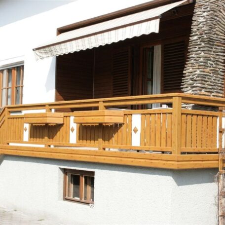 Holzbalkon mit Blumenkästen an einem weißen Haus, Markise über dem Balkon. de HANSEL.kraus metalltechnik gmbh