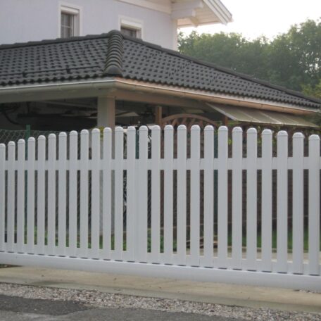 Weißer Gartenzaun aus Kunststoff vor einem modernen Haus mit dunklem Ziegeldach. HANSEL.kraus metalltechnik gmbh