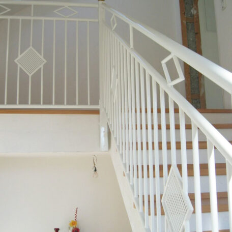 Weißes Treppengeländer mit geometrischen Verzierungen im Innenraum eines Hauses, Tageslicht. HANSEL.kraus metalltechnik gmbh