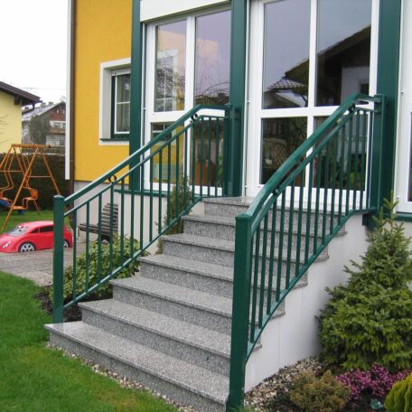 Außentreppe mit grünem Geländer führt zu einer verglasten Eingangstür eines Wohnhauses. HANSEL.kraus metalltechnik gmbh