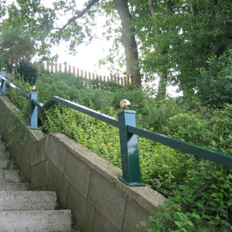 Steintreppe mit grünem Geländer führt an dichten Büschen und Bäumen entlang nach oben. HANSEL.kraus metalltechnik gmbh