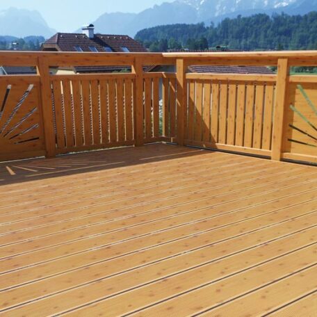 Holzterrasse mit stabilem Geländer, im Hintergrund Berge und Dächer bei sonnigem Wetter. HANSEL.kraus metalltechnik gmbh