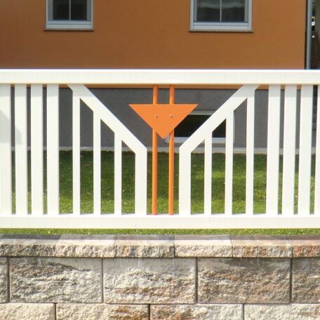 Weißer Gartenzaun mit orangem Pfeildesign vor modernem Haus, grüne Wiese im Hintergrund. HANSEL.kraus metalltechnik gmbh