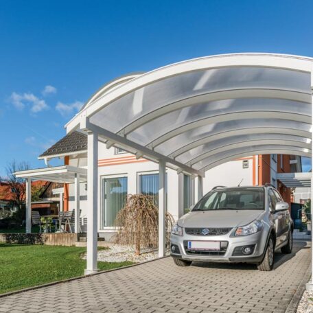 Ein silbernes Auto steht unter einem modernen Carport vor einem Einfamilienhaus bei Sonnenschein. HANSEL.kraus metalltechnik gmbh
