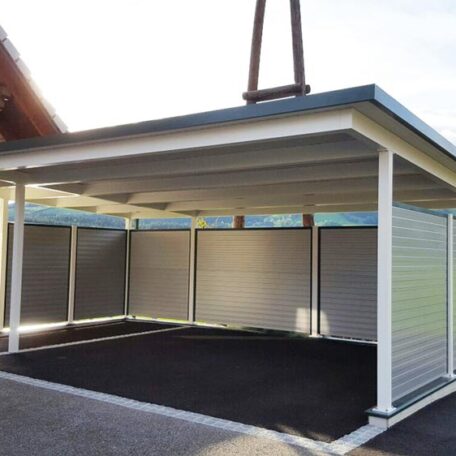 Überdachter Carport mit modernen Seitenwänden auf Asphaltfläche, geeignet für zwei Fahrzeuge. HANSEL.kraus metalltechnik gmbh