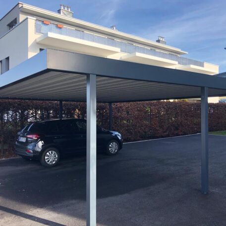 Zwei überdachte Carports mit geparktem Auto auf Asphaltfläche vor einem Wohnhaus. de HANSEL.kraus metalltechnik gmbh