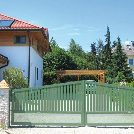Grünes Einfahrtstor vor modernem Haus mit Garten und Holzdach im Sommer. HANSEL.kraus metalltechnik gmbh