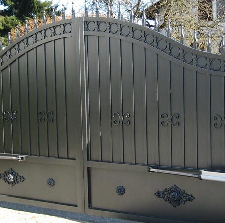 Großes, verziertes Einfahrtstor aus Metall mit geschwungener Form vor einem Wohnhaus. HANSEL.kraus metalltechnik gmbh
