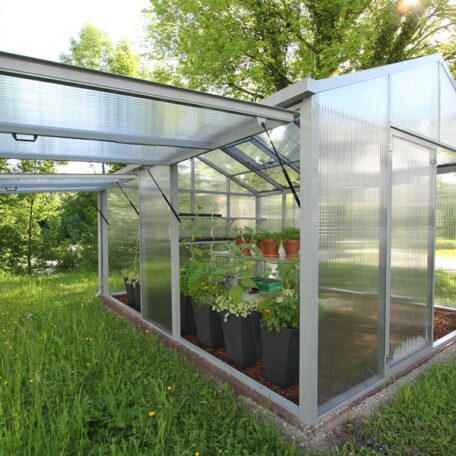 Ein modernes Gewächshaus mit vielen grünen Pflanzen steht auf einer Wiese im Garten. de HANSEL.kraus metalltechnik gmbh