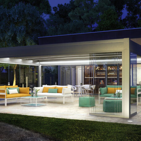 Moderne überdachte Terrasse mit gemütlichen Sofas und stimmungsvoller Beleuchtung bei Nacht, umgeben von Bäumen. HANSEL.kraus metalltechnik gmbh