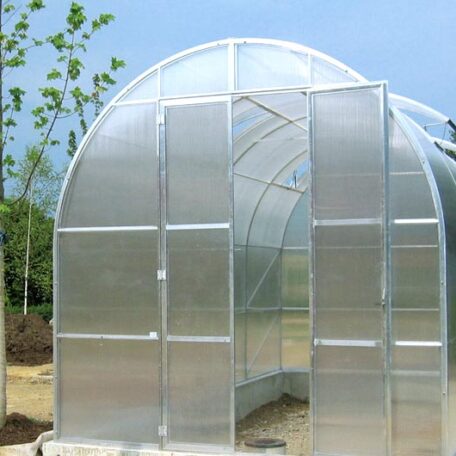 Ein Treibhaus aus transparenten Platten steht im Garten unter blauem Himmel. de HANSEL.kraus metalltechnik gmbh