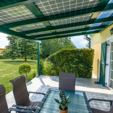 Terrasse mit Solardach und Gartenmöbeln, Blick auf gepflegten Garten bei Tageslicht. HANSEL.kraus metalltechnik gmbh