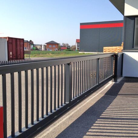 Metallgeländer auf Industriegrundstück mit Gebäuden und Container bei sonnigem Wetter, moderner Kontext. HANSEL.kraus metalltechnik gmbh