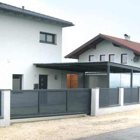 Modernes Einfamilienhaus mit anthrazitfarbenem Zaun und Carport auf einem ruhigen Grundstück. HANSEL.kraus metalltechnik gmbh