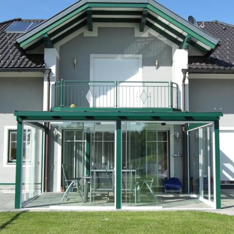 Wintergarten mit Glasdach und grüner Rahmenkonstruktion an Einfamilienhaus, Terrasse davor. HANSEL.kraus metalltechnik gmbh