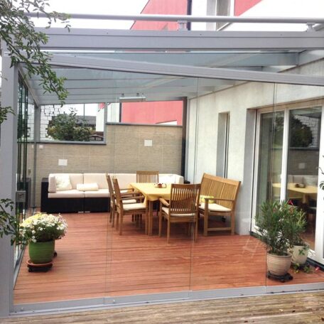 Gemütliche Terrasse mit Holzboden, Sitzgruppe, Sofa, Überdachung und Pflanzen, moderne Hausfassade. de HANSEL.kraus metalltechnik gmbh