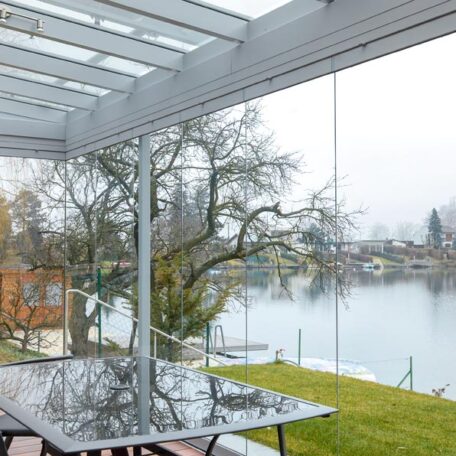Überdachte Terrasse mit Glasdach und Blick auf See, Bäume und Gartenhaus im Winter. HANSEL.kraus metalltechnik gmbh