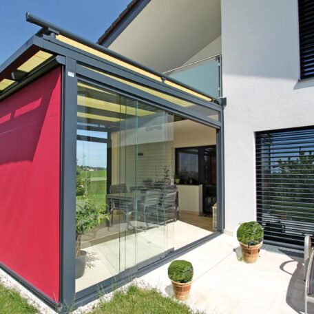 Moderne Terrasse mit Glasüberdachung, rotem Sonnenschutz und Blick ins Wohnzimmer. HANSEL.kraus metalltechnik gmbh