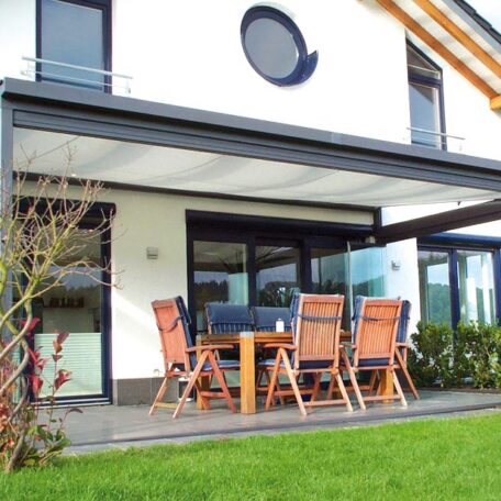 Moderne Terrasse mit Holzmöbeln und Markise an Einfamilienhaus, grüner Garten im Vordergrund. HANSEL.kraus metalltechnik gmbh