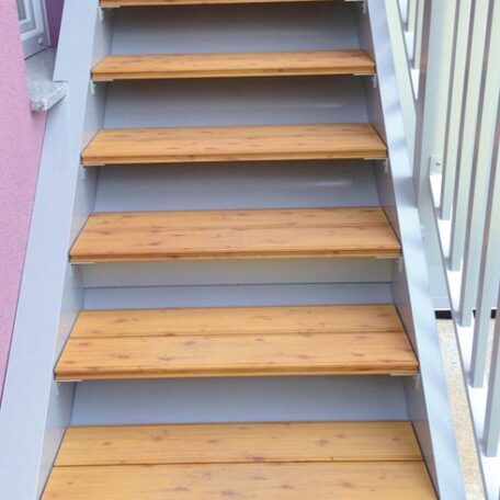 Holztreppe mit weißen Setzstufen und seitlichem Geländer im Außenbereich, Aufsicht. HANSEL.kraus metalltechnik gmbh