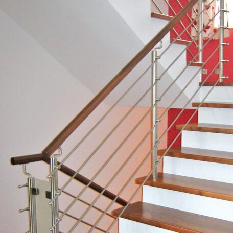 Holztreppe mit Metallgeländer und weißen Setzstufen in modernem Treppenhaus, hell beleuchtet. HANSEL.kraus metalltechnik gmbh