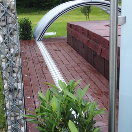 Holzterrasse mit Metallbogen, seitlich bepflanzt, im Hintergrund grüner Rasen, modern gestaltet. HANSEL.kraus metalltechnik gmbh