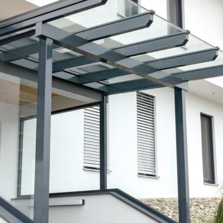 Überdachte Hauseingangstreppe mit moderner Glasvordach-Konstruktion an weißer Hausfassade. HANSEL.kraus metalltechnik gmbh