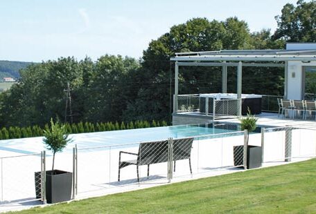 Moderner Infinity-Pool mit Terrasse, zwei Sitzbänken und begrünter Umgebung an sonnigem Tag. de HANSEL.kraus metalltechnik gmbh