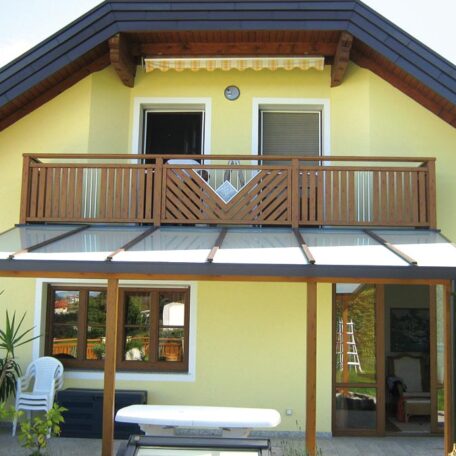 Modernes gelbes Einfamilienhaus mit Balkon, überdachter Terrasse und Holzelementen im Garten. HANSEL.kraus metalltechnik gmbh