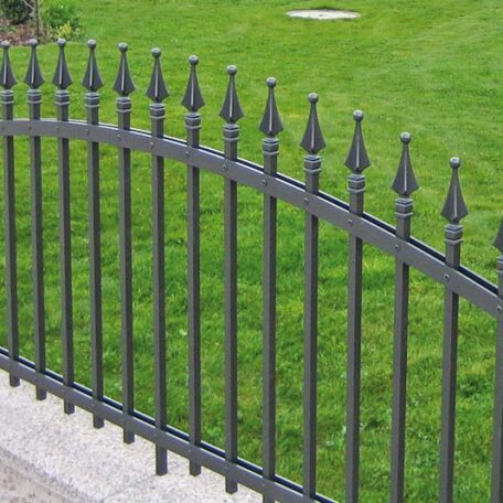 Metallzaun mit Zierspitzen steht vor grünem, gepflegtem Rasen im Außenbereich. HANSEL.kraus metalltechnik gmbh