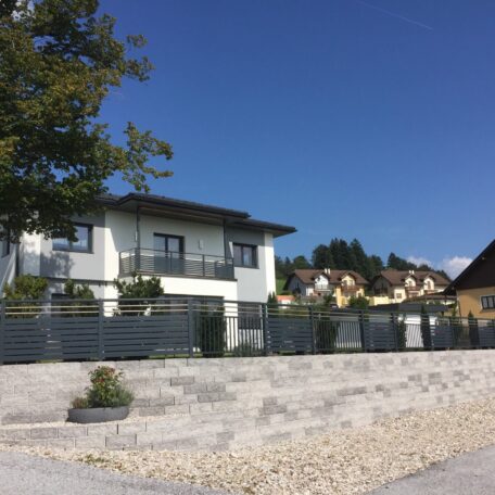 Modernes Einfamilienhaus mit Garten und Zaun unter blauem Himmel in ruhiger Wohngegend. HANSEL.kraus metalltechnik gmbh