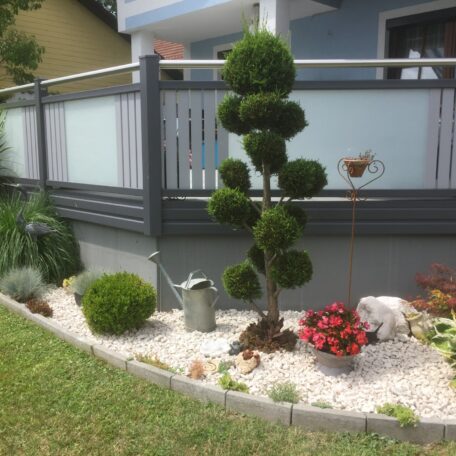 Ziergarten mit Buchsbaum, Kiesbeet, Gießkanne und bunten Blumen vor einer modernen Terrasse. HANSEL.kraus metalltechnik gmbh