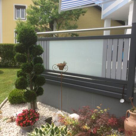 Moderner Sichtschutz mit grauen Lamellen, bepflanzter Kiesstreifen und Buchsbaum im Vorgarten. HANSEL.kraus metalltechnik gmbh