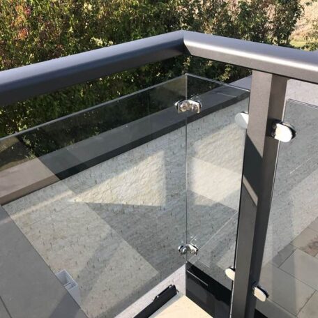 Eine Spinne hängt an ihrem Faden an einer modernen Glasbalkonbrüstung im Sonnenschein. HANSEL.kraus metalltechnik gmbh
