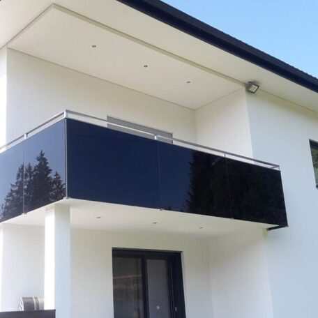 Moderner Balkon mit schwarzer Glasbrüstung an weißem Einfamilienhaus, klarer Himmel im Hintergrund. HANSEL.kraus metalltechnik gmbh