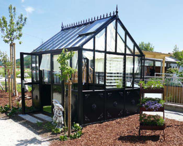 Modernes schwarzes Gewächshaus im Garten mit Pflanzen und Hochbeet bei sonnigem Wetter. de HANSEL.kraus metalltechnik gmbh