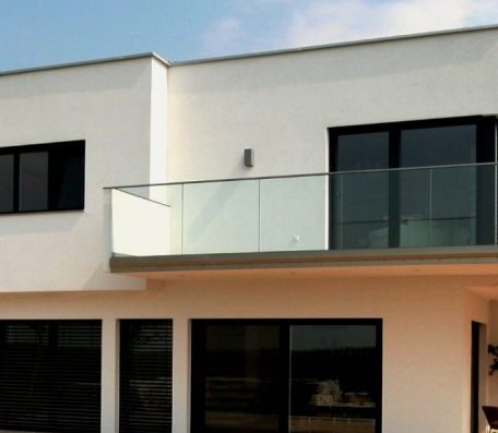 Modernes Einfamilienhaus mit großen Glasfenstern und Balkon, minimalistische Architektur bei Tageslicht. de HANSEL.kraus metalltechnik gmbh
