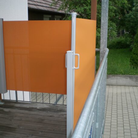 Orange Sichtschutzwand auf einem Balkon mit Metallgeländer und Zugangstür. HANSEL.kraus metalltechnik gmbh