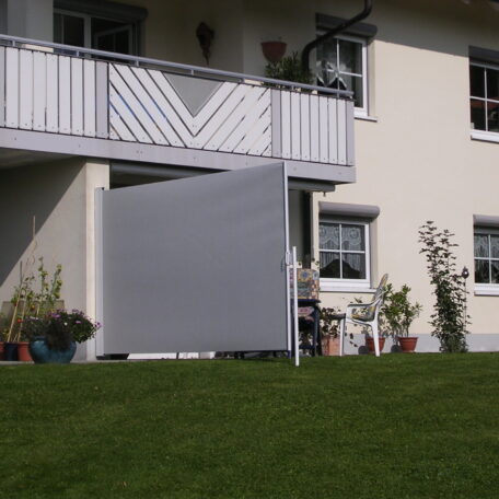 Balkon mit ausziehbarem Sichtschutz, blühende Pflanzen und gepflegter Rasen im Vordergrund. HANSEL.kraus metalltechnik gmbh