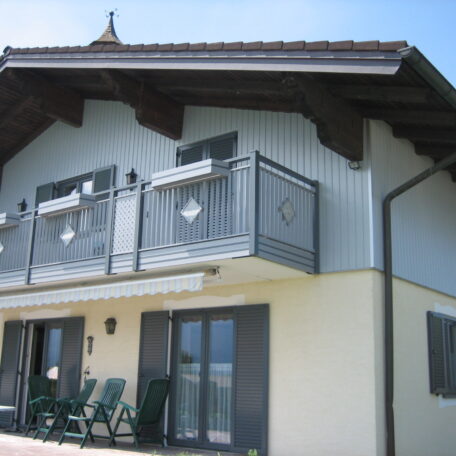 Modernes Einfamilienhaus mit Balkon und Gartenmöbeln vor blauem Himmel. HANSEL.kraus metalltechnik gmbh