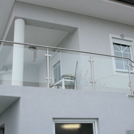 Moderner Balkon mit Glasgeländer und Stühlen an weiß gestrichener Hausfassade, Tageslicht. de HANSEL.kraus metalltechnik gmbh