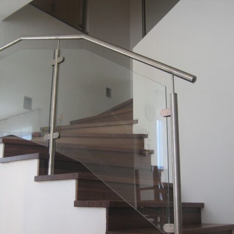 Treppe mit dunklen Holzstufen und modernem Glasgeländer in einem hellen Treppenhaus. HANSEL.kraus metalltechnik gmbh